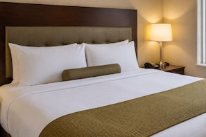 Een hotelkamer met een bed, hoofdeinde, bedlamp en nachtkastje.