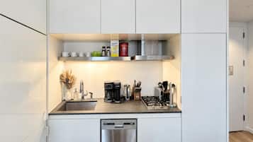 A modern kitchen with white cabinetry, a stainless steel dishwasher, a coffee maker, and a gas stove.
