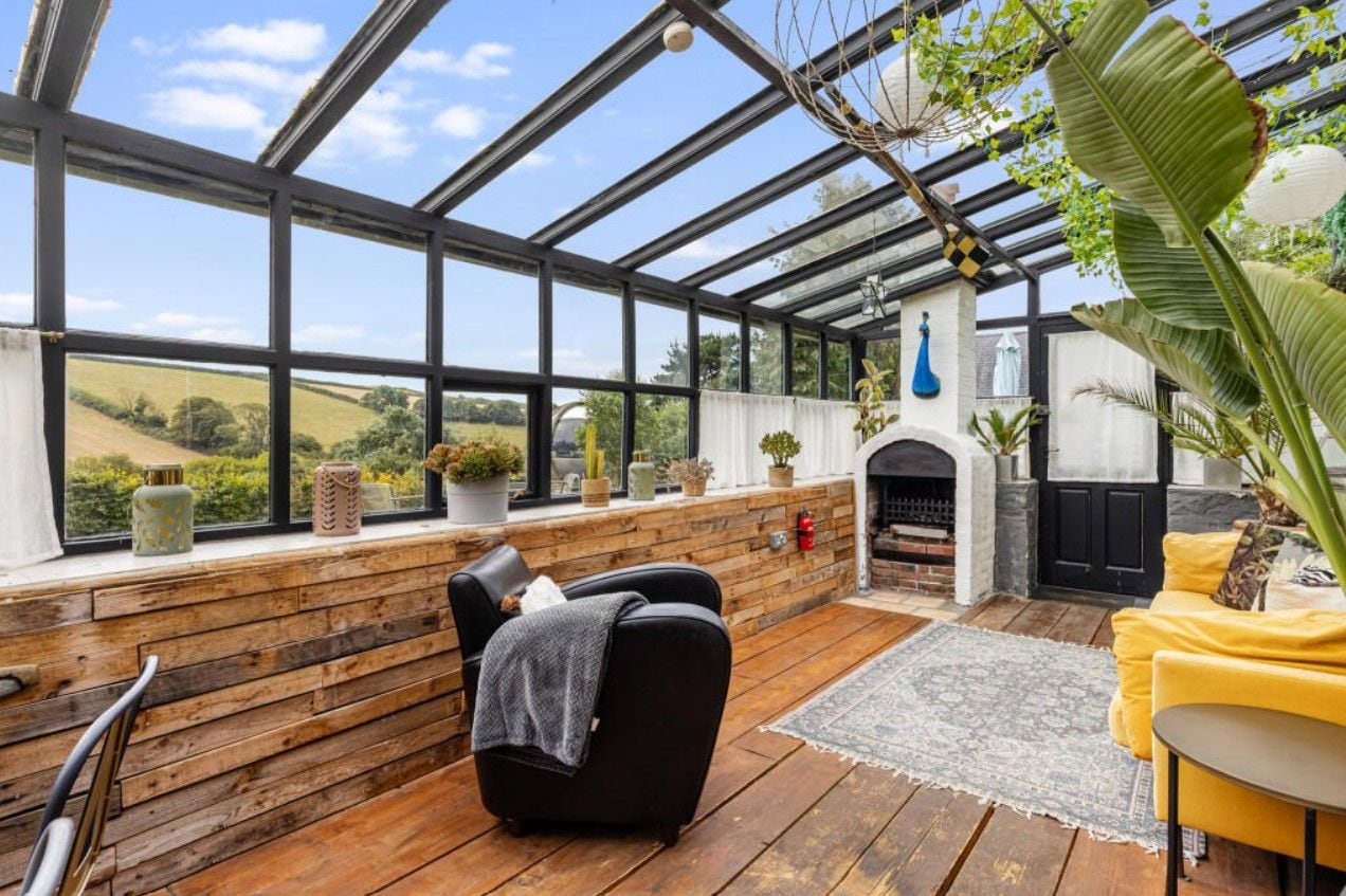 Un invernadero con chimenea, zona de estar y plantas en macetas.