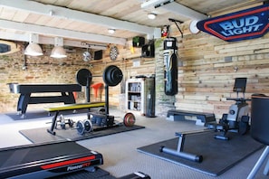 A gym with weightlifting equipment, a punching bag, and a treadmill. - Valley cottage with hot tub (Kingsbridge)