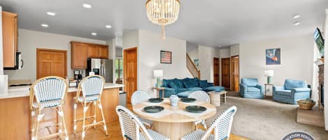 A modern kitchen with wooden cabinets, a stainless steel refrigerator, and a dining area with a round table and wicker chairs.