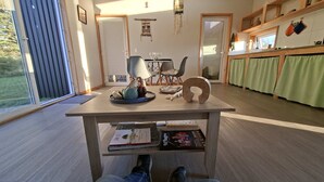 Eine moderne Küche mit Essbereich, einem großen Fenster und einem Holztisch mit Büchern und einem Wasserkocher.