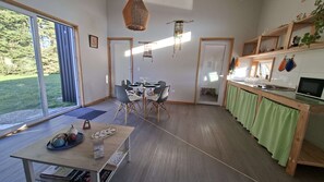 A modern kitchen with a dining area, wooden flooring, and a view of the outdoors.