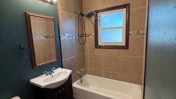 A bathroom with a bathtub, a sink, a toilet, and a window with a view.