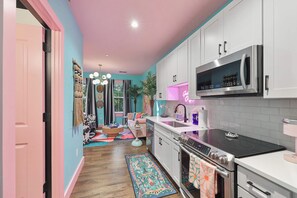Une cuisine moderne avec des meubles blancs, une cuisinière en acier inoxydable et un four à micro-ondes.