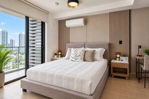 A modern bedroom with a large bed, a city view, and a built-in air conditioning unit. - San Francisco 2BR | Balcony, City Views & Pool (Panamá)