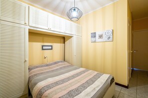 A bedroom with a bed, a hanging light fixture, and a wall-mounted picture. - Studio Apartment Zeedijk With Ocean View (Blankenberge)