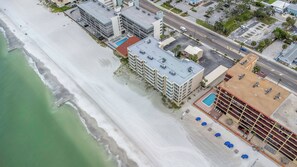 Eine Vogelperspektive zeigt ein Küstenhotel mit Strandlage, mehreren Gebäuden und einem Parkplatz.