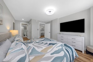 A modern bedroom with a large bed, a TV mounted on the wall, and a walk-in closet. - Cozy Oceanfront 2-bedroom condo in Madeira Beach - Sleeps 6 (Madeira Beach)