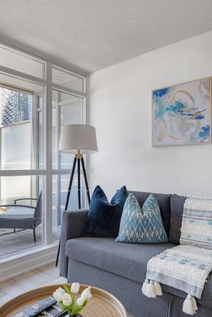 A modern living room with a grey sofa, a floor lamp, and a painting on the wall. - Sleek Downtown Oasis  Modern Retreat in Toronto | Parking Available (Toronto)
