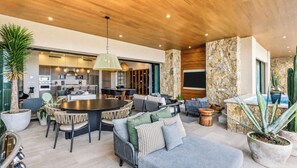 A modern kitchen with built-in appliances, a dining area with a round table and chairs, and a cozy seating area with sofas and cushions. - Sophisticated 4BR Oceanview Retreat w/ Hot Tub (Cabo San Lucas)