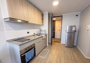 A compact kitchen with a built-in oven, a stainless steel refrigerator, and a microwave. - Mirador Central by Domus Travels (Estación Central)