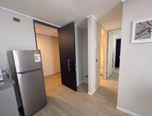 A modern kitchen with a built-in refrigerator, a dark door, and a hallway leading to another room. - Mirador Central by Domus Travels (Estación Central)