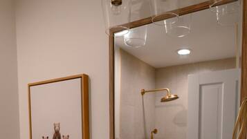 A bathroom with a large mirror, a bathtub, a shower, and a sink.