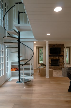 Un interior moderno con una escalera espiral, una chimenea de piedra y una zona de estar acogedora.