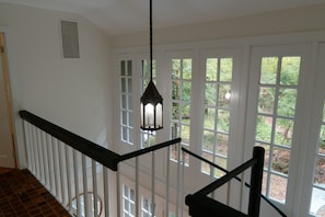 Una escalera con barandillas blancas y un farol colgante.