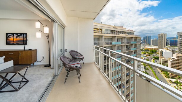 Un balcon donnant sur un paysage urbain, un canapé, un fauteuil et un tableau.