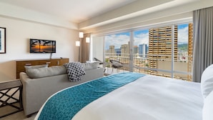 Une chambre d’hôtel avec un lit, un canapé, une télévision, une vue sur la ville et un balcon.