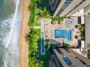 A rooftop pool area with lounge chairs and a swimming pool, overlooking a beach. - Mahana #311 New Oceanfront Corner Remodel - 2 bed/2 bath (Lahaina)