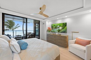 Ein Schlafzimmer mit einem großen Bett, einem Fernseher, einer Couch und einem Balkon mit Meerblick.