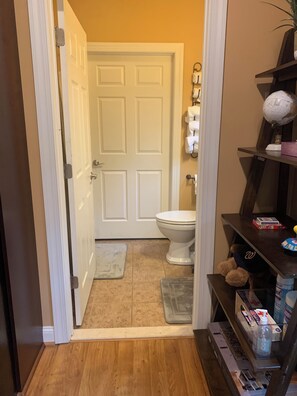 Un bagno con una porta bianca, un water, uno scaffale con articoli da toilette e un globo su un supporto.