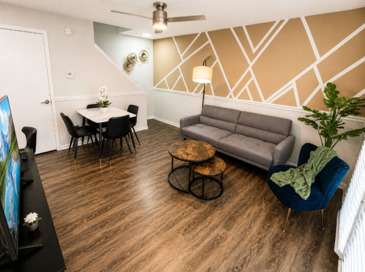 Ein modernes Wohnzimmer mit grauem Sofa, rundem Couchtisch und blauem Sessel.