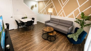 Ein modernes Wohnzimmer mit grauem Sofa, rundem Couchtisch und blauem Sessel.