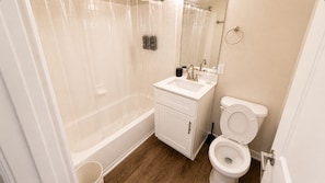 Un baño con bañera, inodoro, lavamanos y espejo.