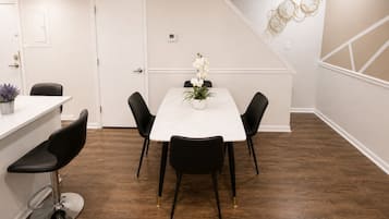 A dining area with a white table, black chairs, and a potted plant.