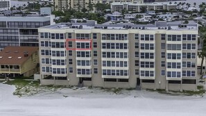 Un edificio de varios pisos con techo plano, ventanas amplias y un cuadrado rojo que delimita una zona específica.