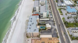 Vista aérea de un hotel costero con ubicación frente a la playa, estacionamiento y piscina.