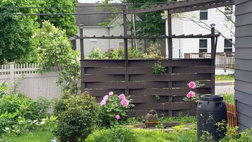 A garden with a stone pathway, a wooden fence, and various plants.