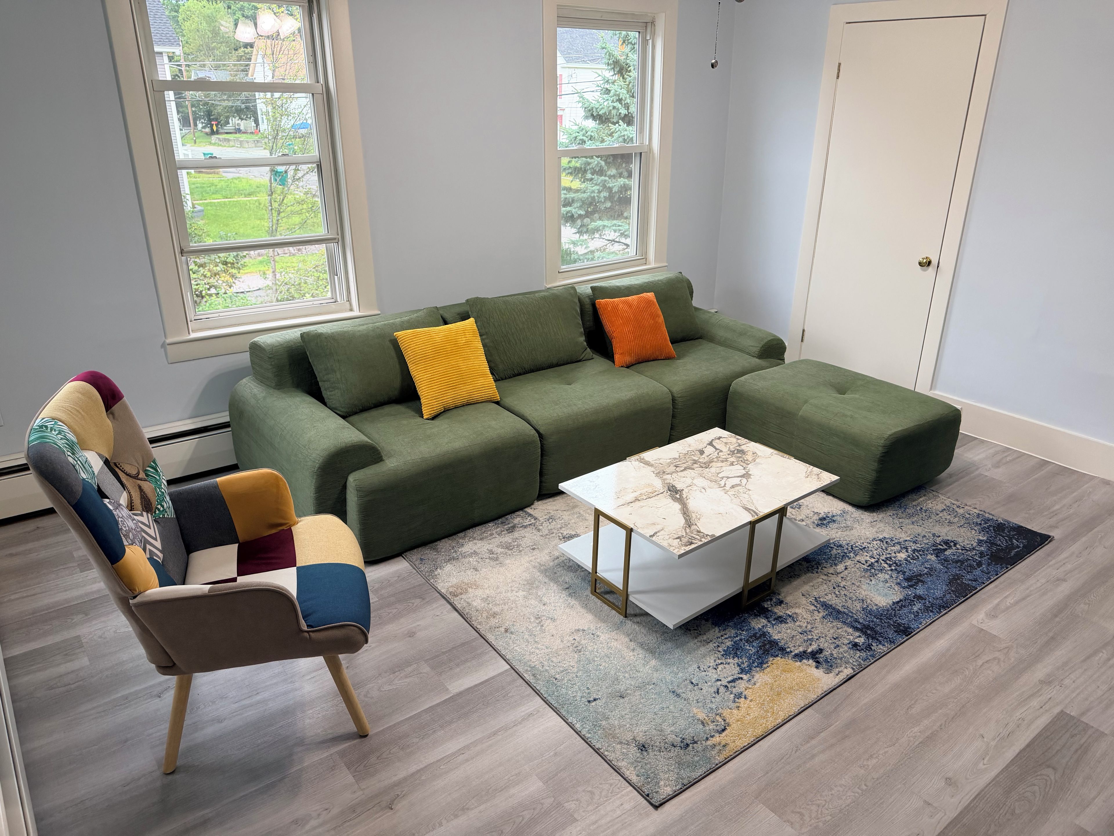Een moderne woonkamer met een modulaire bank, een salontafel en een kamerkleed met een patroon.
