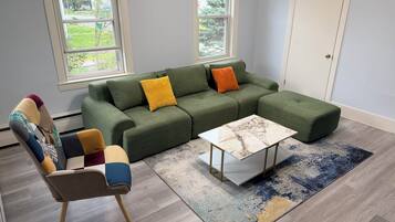 Een moderne woonkamer met een modulaire bank, een salontafel en een kamerkleed met een patroon.