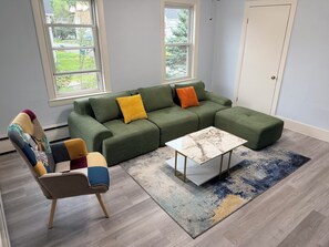 Uma sala de estar moderna com um sofá seccional, uma mesa de centro e um tapete estampado.