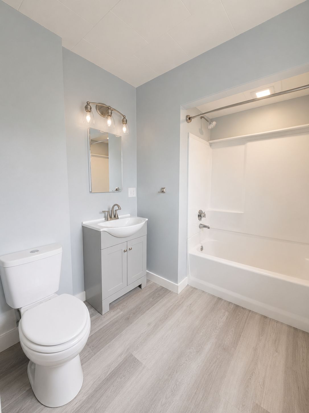 A bathroom with a toilet, sink, mirror, and bathtub.