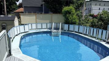 A rectangular swimming pool with a wooden deck and a metal ladder.