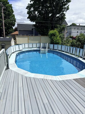 Piscina retangular com deck de madeira e escada de metal.