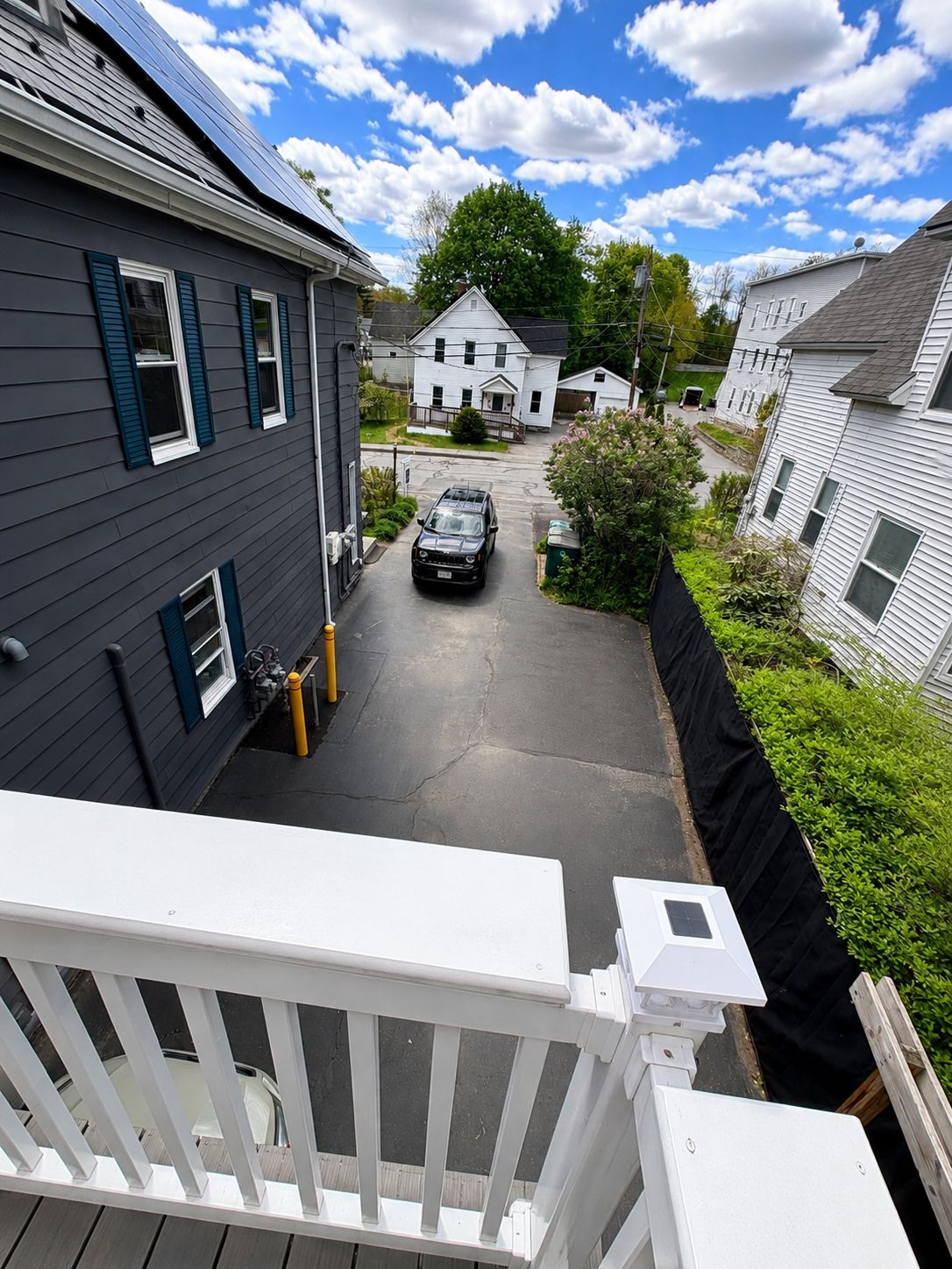 A residential street with houses, a driveway, and a parked car.