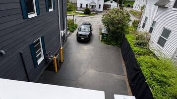 A residential street with houses, a driveway, and a parked car.