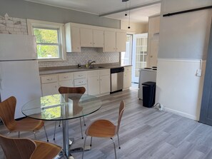 A modern kitchen with white cabinets, a glass dining table, and wooden chairs. - Fitchburg hideaway Home (Fitchburg)
