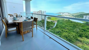 Ein Balkon mit Esstisch, gedeckt für vier Personen, mit Blick auf Stadt und Grünflächen.