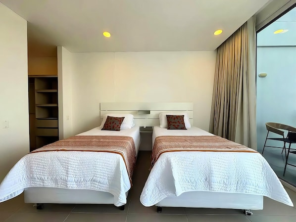 Een hotelkamer met twee bedden, een kledingkast, een stoel en uitzicht op het omliggende landschap.