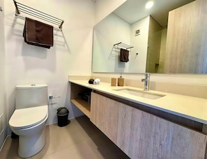 Een moderne badkamer met toilet, wastafel en spiegel.