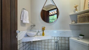 A bathroom with a white sink, a toilet, a shower, and a mirror. - Vrbo Property (Açu da Torre)