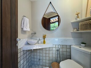 Un baño con lavamanos blanco, inodoro, ducha y espejo.