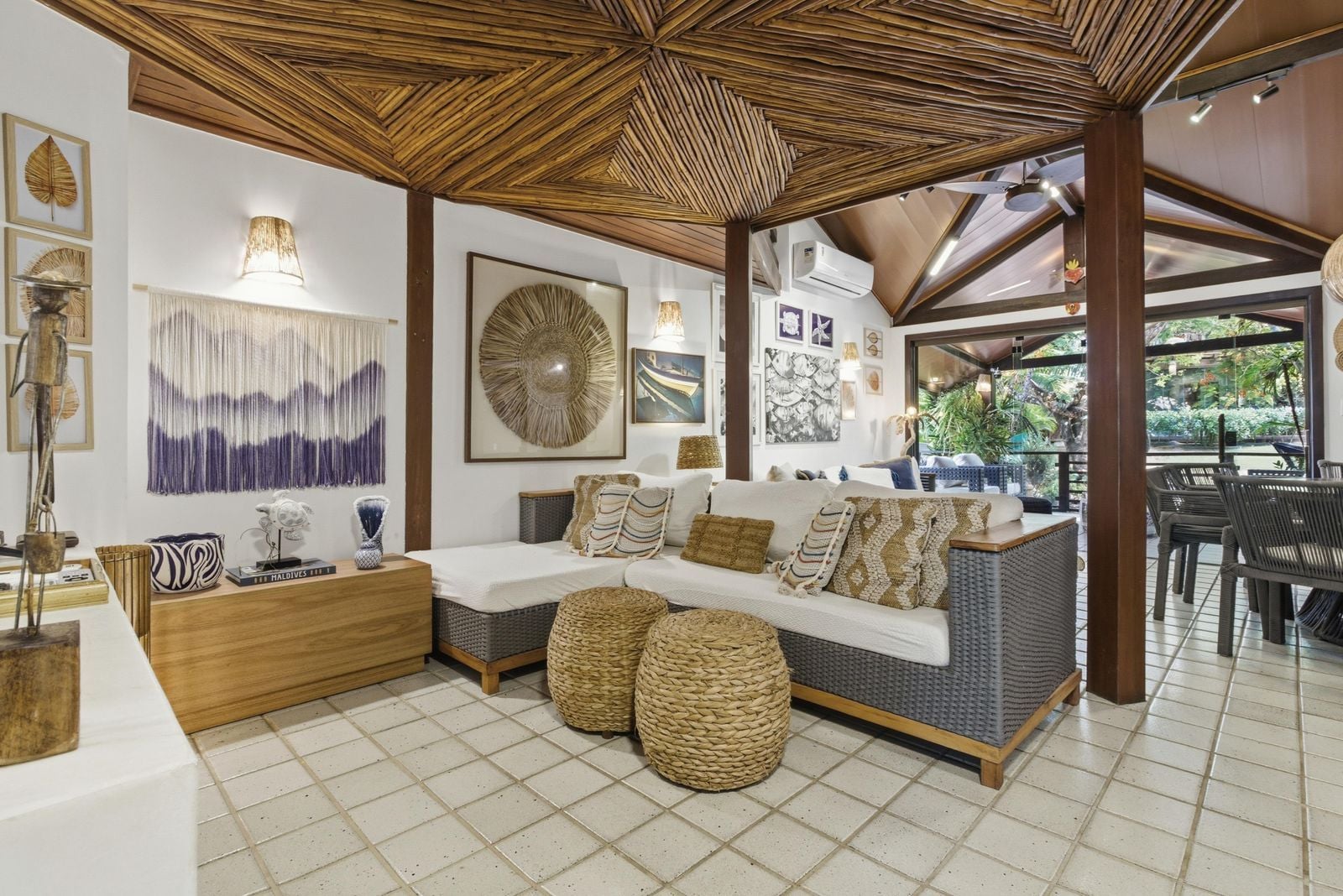 A modern living room with a wooden ceiling, a sofa set, and a dining area with chairs.