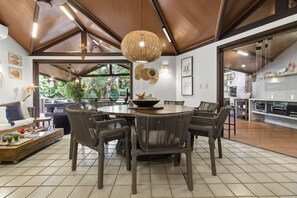 Un comedor moderno con una mesa redonda y sillas de mimbre, una lámpara colgante y vistas al exterior.
