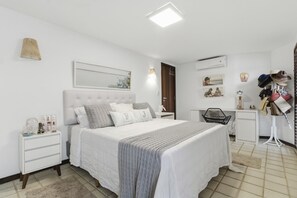 Un dormitorio con cama, mesitas de noche, un escritorio y un zapatero.