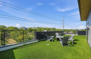 A rooftop terrace with artificial grass, outdoor seating, and a view of the cityscape. - Modern Condo & Private Terrace w/ Downtown View (Nashville)